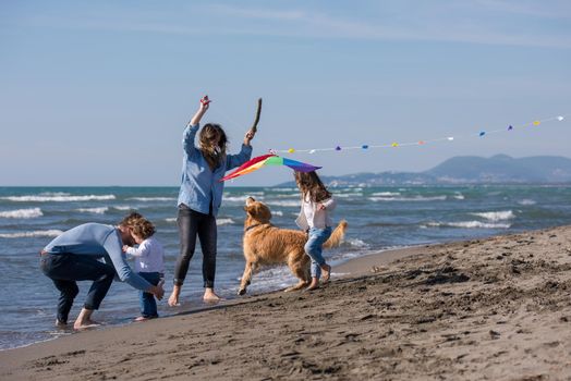happy young family with kids having fun with a dog and  kite at beach during autumn day