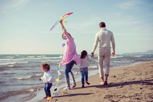 young family with kids resting and having fun with a kite at beach during autumn day filter