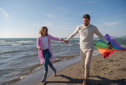 Young Couple having fun and Playing With A Kite On The Beach at autumn day