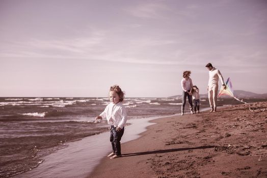 young family with kids resting and having fun with a kite at beach during autumn day filter