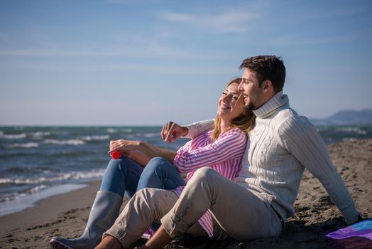 Young Couple having fun and making soap bubbles On The Beach at autumn day