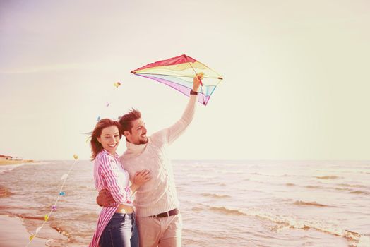 Young Couple having fun and Playing With A Kite On The Beach at autumn day filter