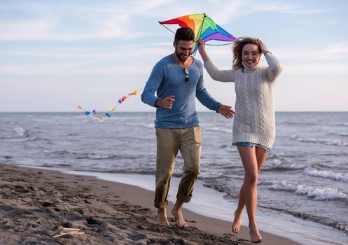 Young Couple having fun and Playing With A Kite On The Beach at autumn day