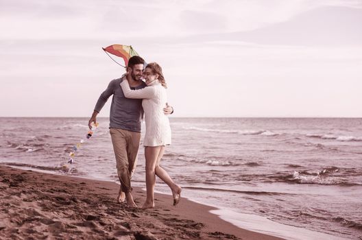 Young Couple having fun and Playing With A Kite On The Beach at autumn day filter