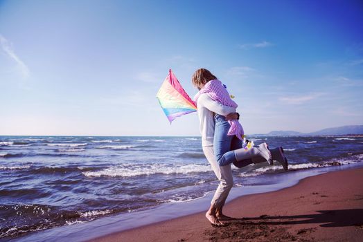 Young Couple having fun and Playing With A Kite On The Beach at autumn day filter