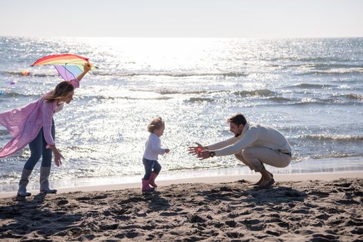 young family with kids resting and having fun with a kite at beach during autumn day