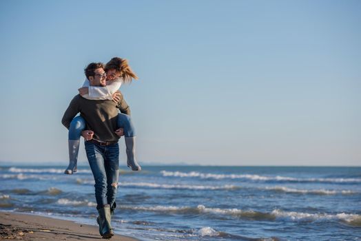 Men Giving Piggy Back Rides to his girlfriend At Sunset By The Sea, autumn time