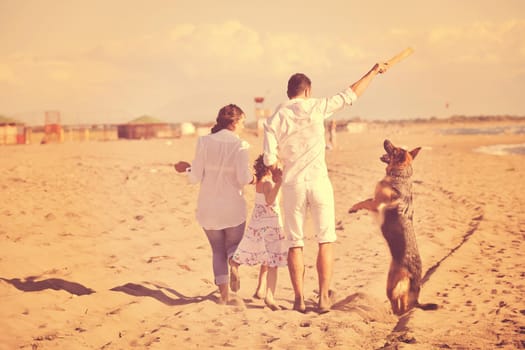 happy young family in white clothing have fun and play with beautiful dog at vacations on beautiful beach 