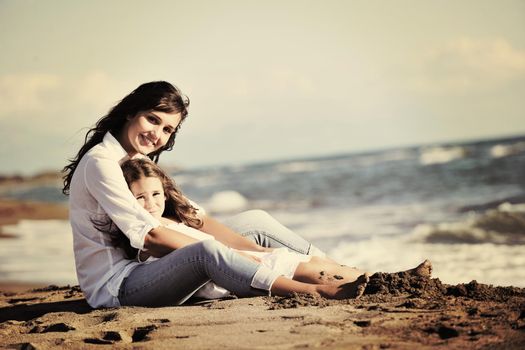 family portrait of young beautiful mom and daughter on beach