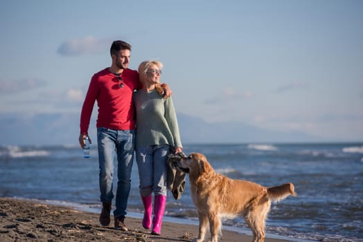 Couple Running On The Beach Holding Their Hands with dog On autmun day