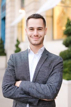 Portrait of young caucasian boy wearing grey suit outside. Concept of successful businessman and male fashion.