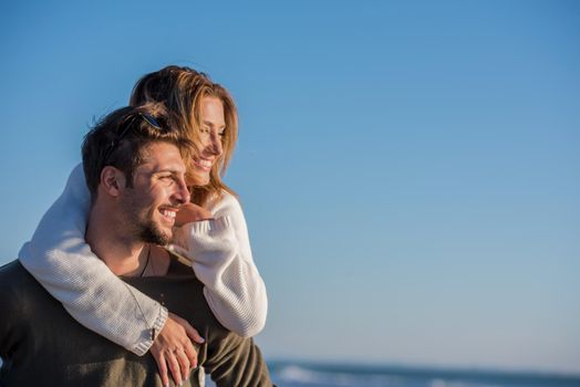 Men Giving Piggy Back Rides to his girlfriend At Sunset By The Sea, autumn time