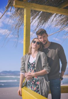 Happy couple enyojing time together on beach during autumn day colored filter