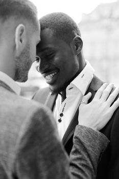 Black and white photo of caucasian man hugging afro american boy, wearing suit. Concept of relationship and same sex couple.