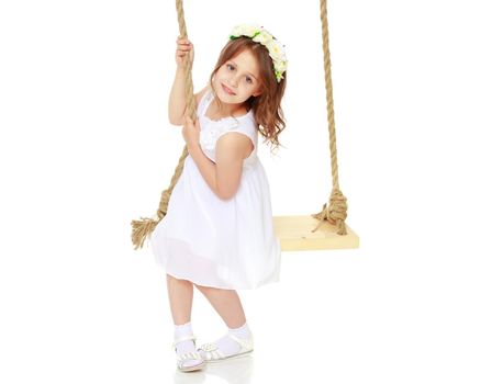 A little girl is swinging on a rope swing. The concept of a happy childhood, summer holidays, playing in a playground or in a kindergarten. Isolated on white background.