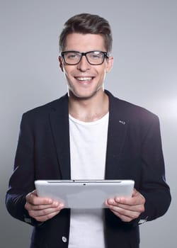 young man holding a tablet in his hands, looking at something and smiling