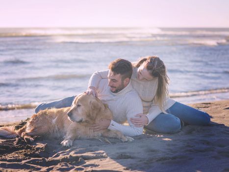 Couple With A Dog enjoying time  together On The Beach at autumn day colored filter