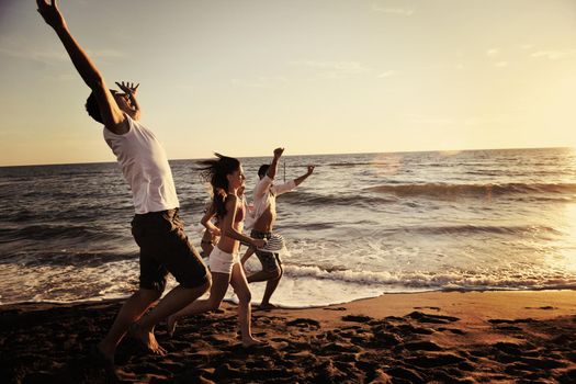 happy young people group have fun white running and jumping on beacz at sunset time