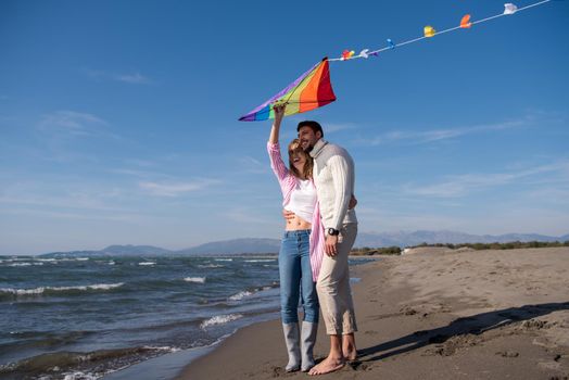 Young Couple having fun and Playing With A Kite On The Beach at autumn day