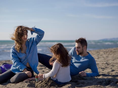 Family with little daughter resting and having fun at beach during autumn day