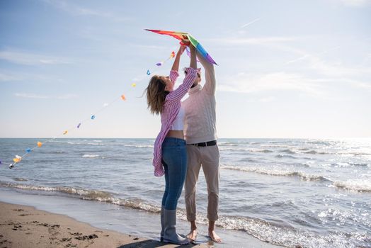 Young Couple having fun and Playing With A Kite On The Beach at autumn day