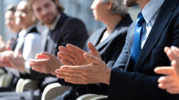 Business partners hands applauding at meeting, people sitting in a row at conference