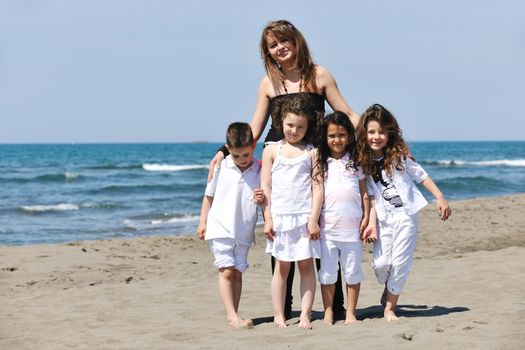 group portrait of happy childrens with young female  teacher on beach
