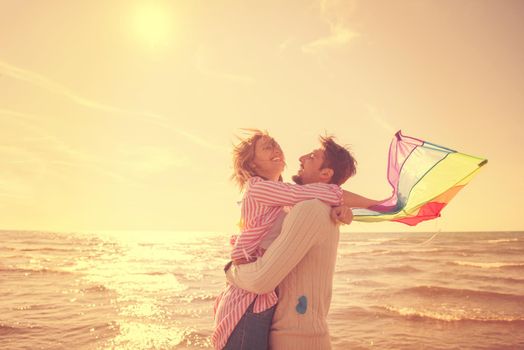 Young Couple having fun and Playing With A Kite On The Beach at autumn day filter