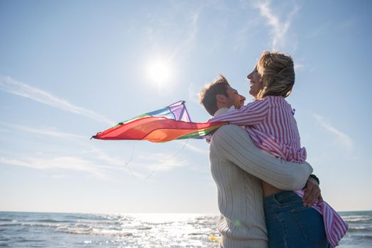 Young Couple having fun and Playing With A Kite On The Beach at autumn day