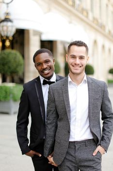 Afro american and caucasian gays walking outside in city. Concept of same sex male couple.