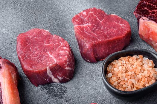 Raw filet mignon or eye steaks with herbs and spices set, on gray stone background