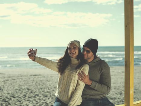 Very Happy Couple In Love Taking Selfie On The Beach in autmun day colored filter