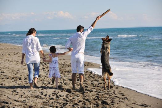 happy young family in white clothing have fun and play with beautiful dog at vacations on beautiful beach 