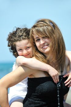 group portrait of happy childrens with young female  teacher on beach