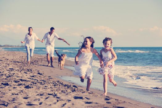 happy young family in white clothing have fun and play with beautiful dog at vacations on beautiful beach 