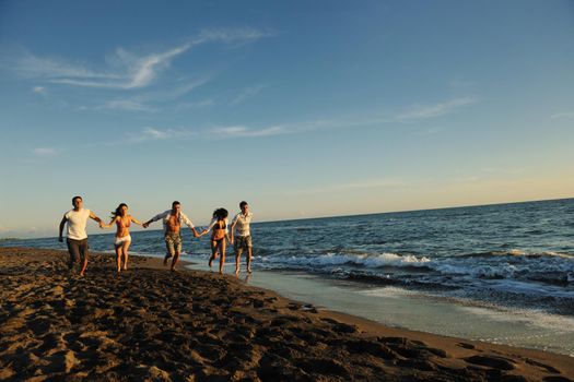 happy young people group have fun white running and jumping on beacz at sunset time