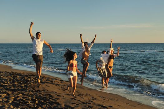 happy young people group have fun white running and jumping on beacz at sunset time