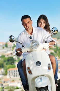 Portrait of happy young love couple on scooter enjoying themselves in a park at summer time