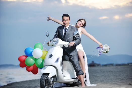 wedding sce of bride and groom just married couple on the beach ride white scooter and have fun