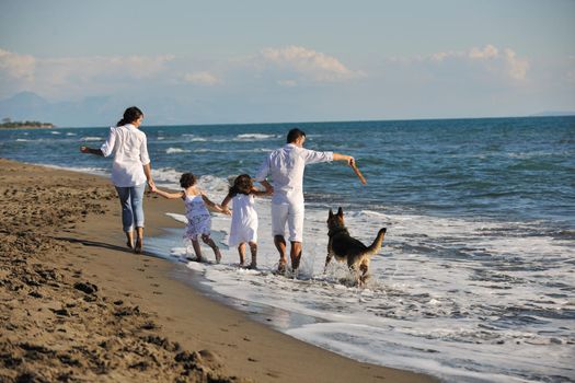 happy young family in white clothing have fun and play with beautiful dog at vacations on beautiful beach 