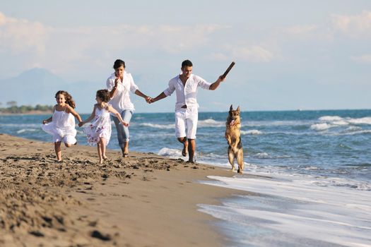 happy young family in white clothing have fun and play with beautiful dog at vacations on beautiful beach