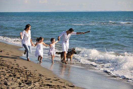 happy young family in white clothing have fun and play with beautiful dog at vacations on beautiful beach 