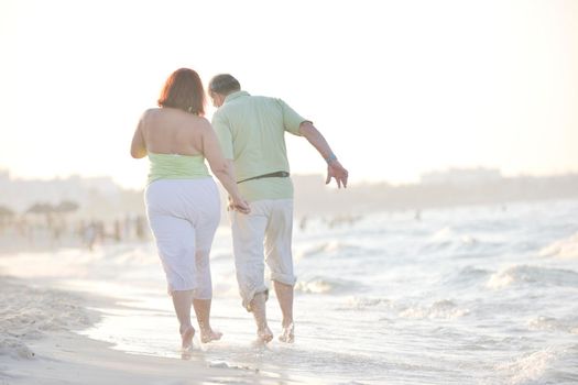 happy senior mature elderly people couple have romantic time on beach at sunset 