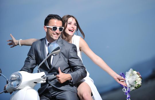 wedding sce of bride and groom just married couple on the beach ride white scooter and have fun