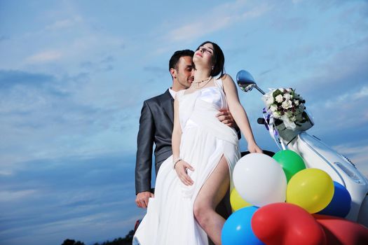 wedding sce of bride and groom just married couple on the beach ride white scooter and have fun