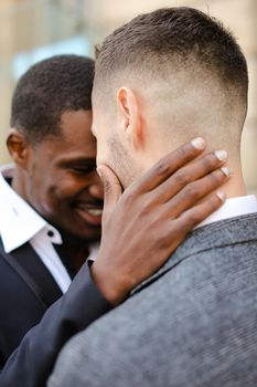 Afro american man hugging caucasian guy, wearing suit. Concept of same sex couple and gays.