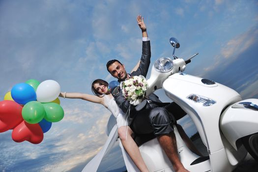 wedding sce of bride and groom just married couple on the beach ride white scooter and have fun