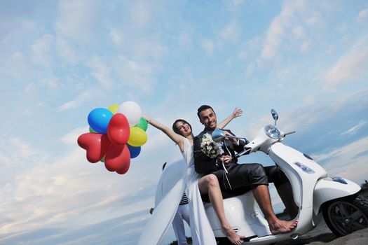 wedding sce of bride and groom just married couple on the beach ride white scooter and have fun