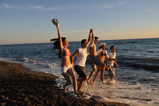 happy young people group have fun white running and jumping on beacz at sunset time