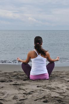 young woman meditating yoga in lotus positin on the beach at early morning